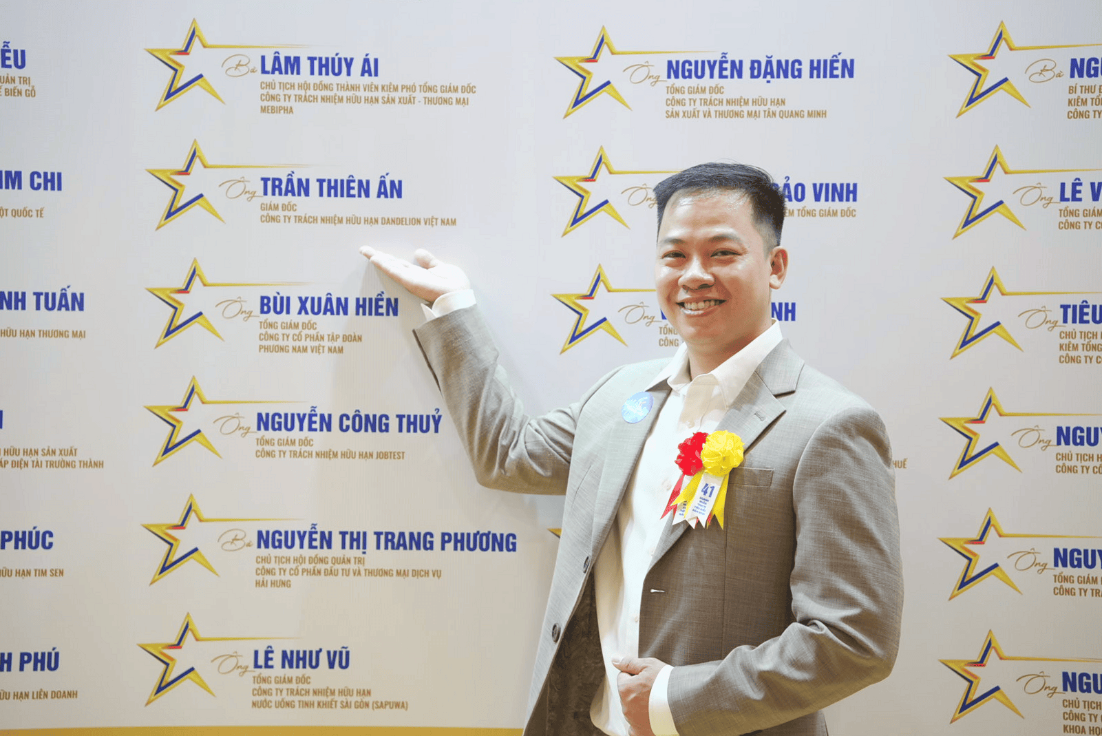 Ông Trần Thiên Ấn đứng cạnh bảng vinh danh ghi tên mình và chức danh Giám đốc Dandelion Việt Nam