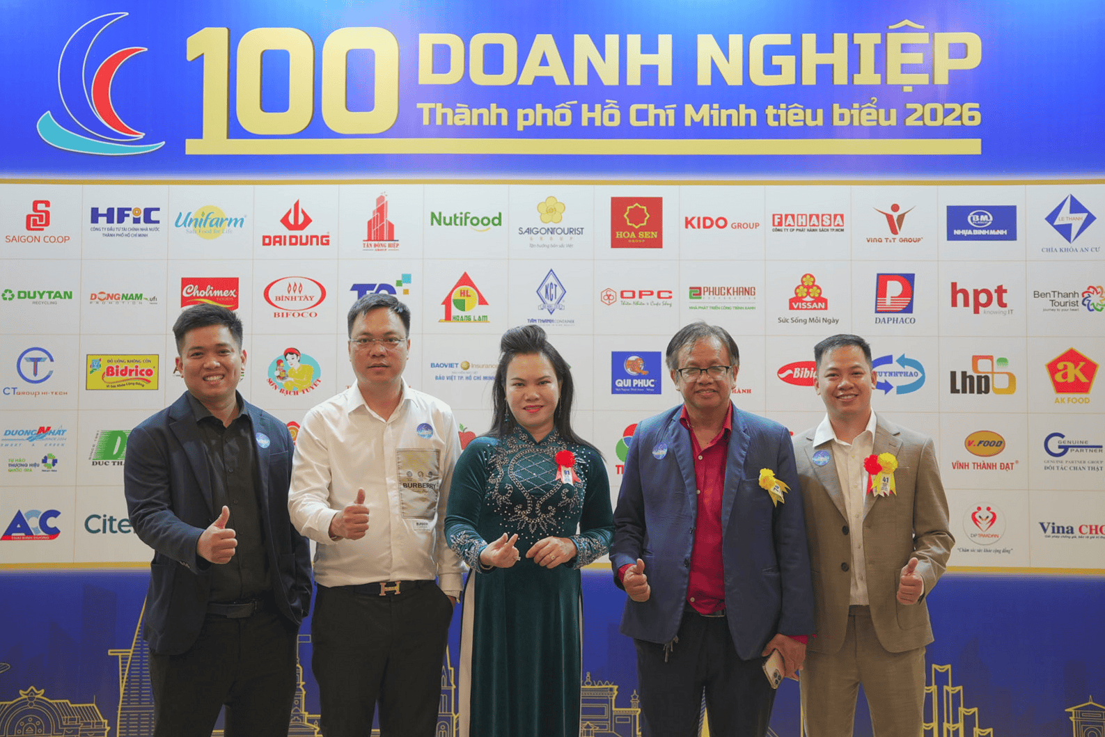 Năm đại diện và khách mời giơ ngón tay cái trước bảng 100 doanh nghiệp tiêu biểu 2026